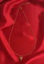 A delicate gold-toned necklace with a beaded satellite chain and a small, puffed heart pendant.