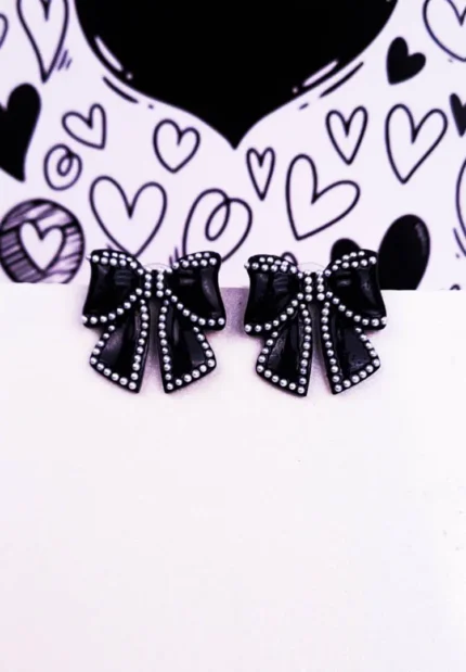 Elegant black bow-shaped earrings outlined with white pearls and featuring a secure push-back closure.