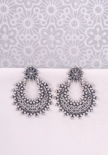 Large, crescent-shaped oxidized silver drop earring, also known as a Chandbali, featuring a highly textured surface of dense, tiny seed bead clusters and a small floral stud at the top.
