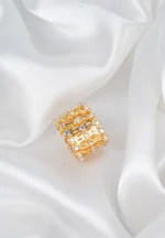 Wide-band ring with openwork lace pattern and radiant faceted crystals for statement sparkle.