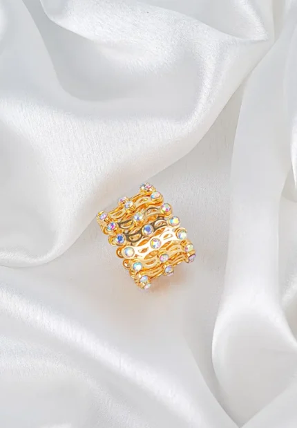 Wide-band ring with openwork lace pattern and radiant faceted crystals for statement sparkle.