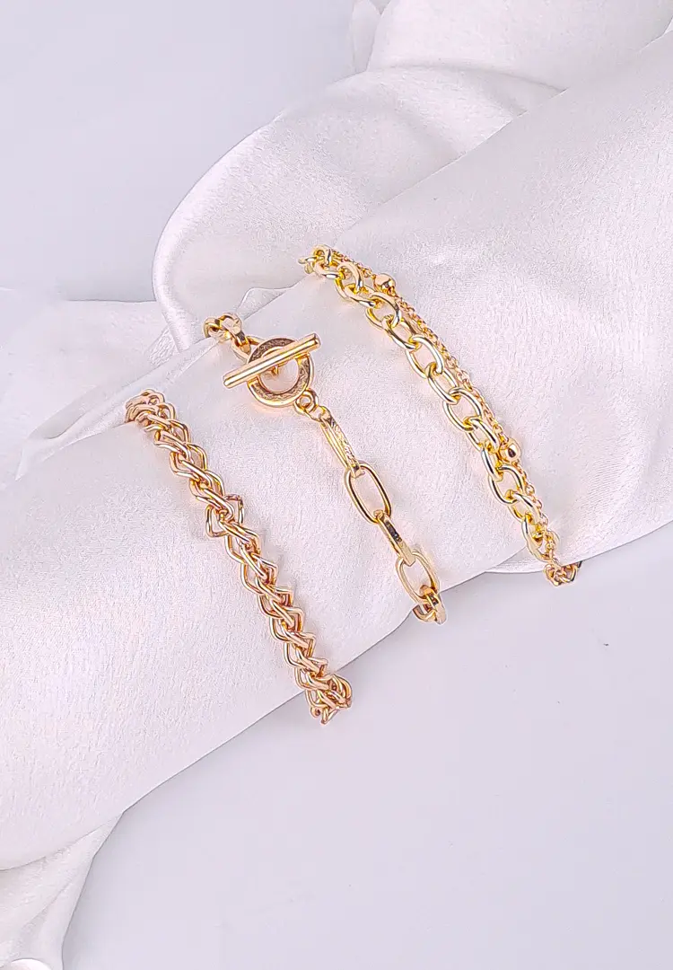 th - 2025-12-03T124958.488 Pack of three gold-tone chain bracelets in assorted link designs with polished finish and secure clasp closures, styled for a layered and statement look