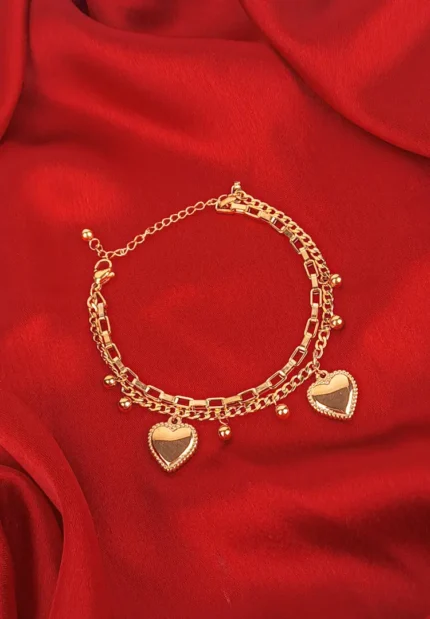 Layered gold bracelet with heart charms, polished beads, and mixed chains.