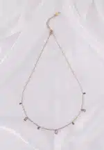 A gold-toned bracelet with a thin chain and small, dangling rectangular white gems.