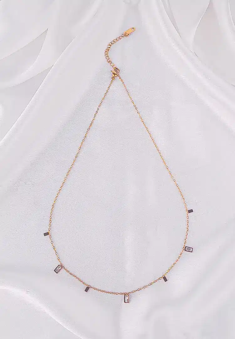 th - 2025-12-06T133256.317 A gold-toned bracelet with a thin chain and small, dangling rectangular white gems.