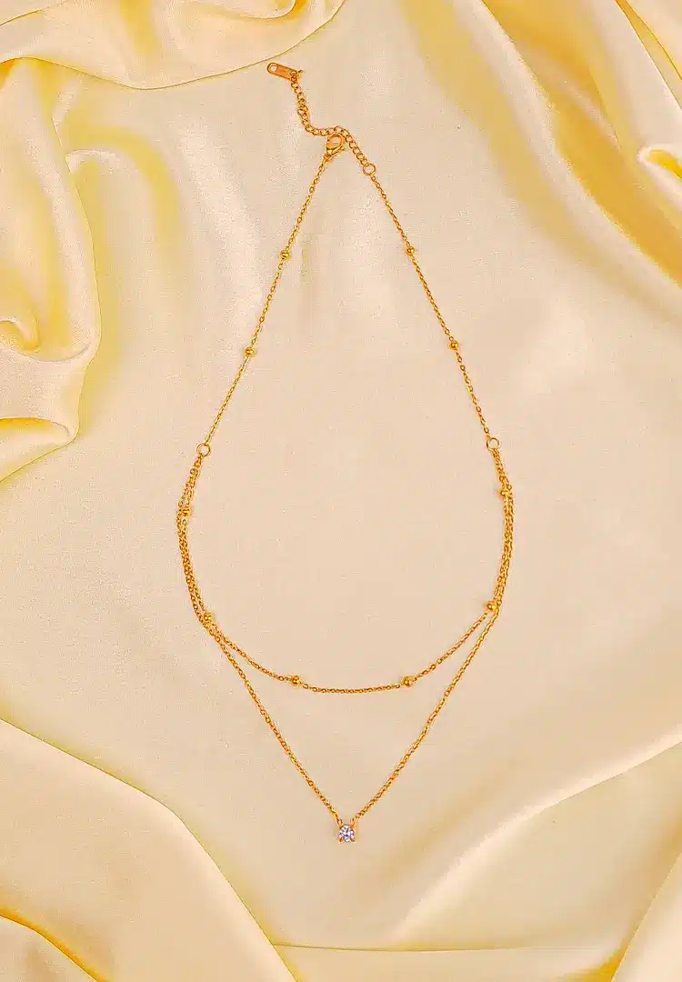 th - 2025-12-06T151623.023 Gold layered necklace with bead accents, crystal charm, and adjustable lobster clasp.