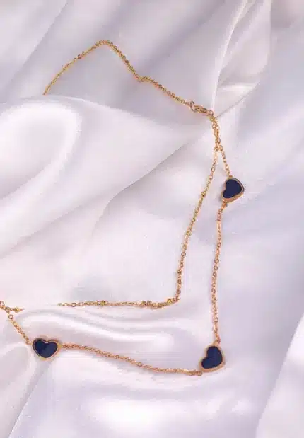 Layered gold necklace with black enamel heart pendants and lobster clasp.