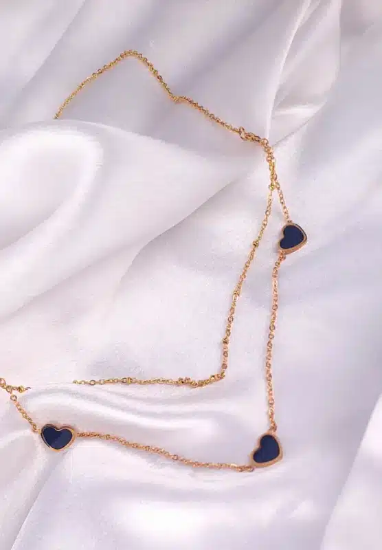 Layered gold necklace with black enamel heart pendants and lobster clasp.