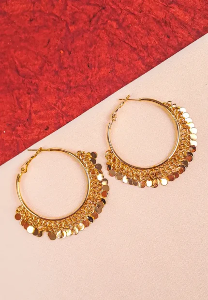 Large, shiny gold-tone hoop earring with multiple small, round coin or disc charms dangling from delicate chains along the bottom curve, creating a fringe effect.