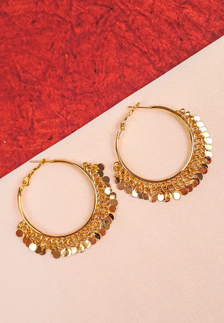 th - 2025-12-06T180457.945 Large, shiny gold-tone hoop earring with multiple small, round coin or disc charms dangling from delicate chains along the bottom curve, creating a fringe effect.