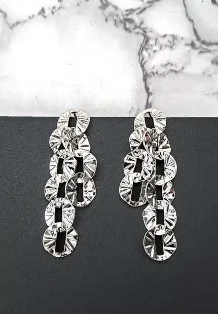 Silver drop earrings with sculpted textured discs and push-back closure, featuring a contemporary geometric design.