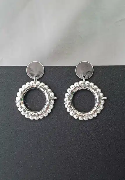 Round silver hoop earrings framed with pearls, featuring reflective studs and push-back closures.
