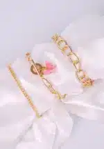 Three gold chain bracelets, one with large links, one classic, one with a pink butterfly charm and adjustable closures.