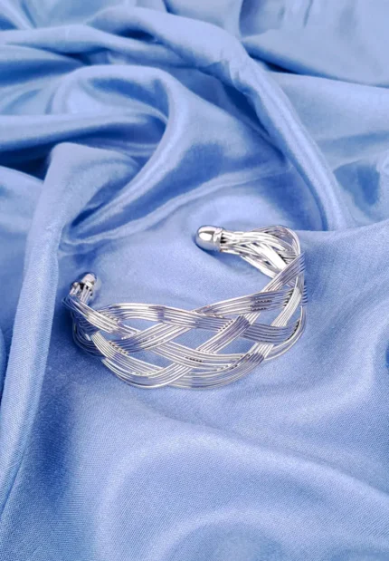 a wide gold-colored cuff bracelet featuring an intricate, woven or braided design made from multiple thin metal strands