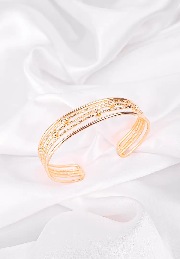 th - 2025-12-12T165707.809 a gold-colored bangle bracelet composed of multiple textured bands, including beaded and dotted designs