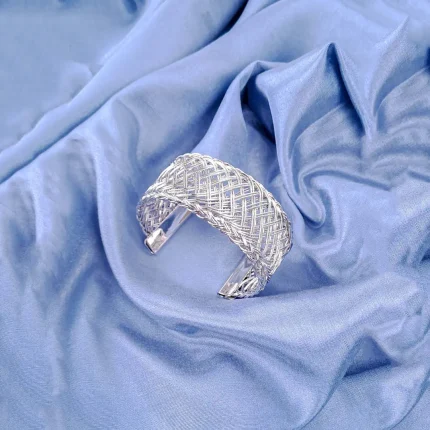 The bracelet features a dense, intricate, and evenly woven mesh pattern made from numerous thin, shiny gold wires, giving it a rich texture. The cuff is open at the bottom.